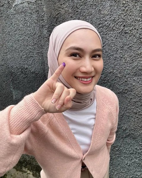 Melody Laksani mengenakan top putih dan cardigan warna pink pastel. Ia melengkapi penampilannya denganhijab warna nude pink.