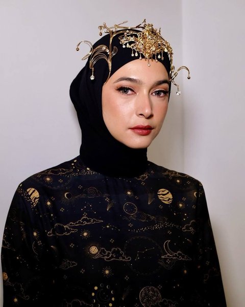 Penampilannya semakin sempurna dengan headpiece emas cantik dan unik yang menambah pesona keanggunannya.<br>