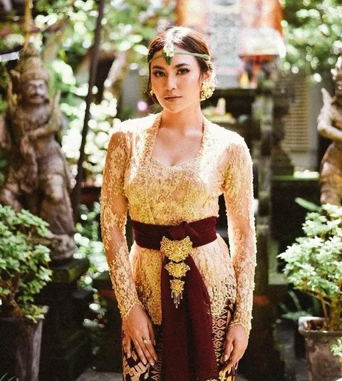 Mahalini tampak elegan dengan kebaya warna gold dengan kain warna maroon serta aksesori unik.