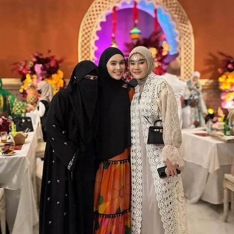 Kartika Putri hadir dengan dress warna oranye cerah yang dipadukan dengan hijab warna hitam.