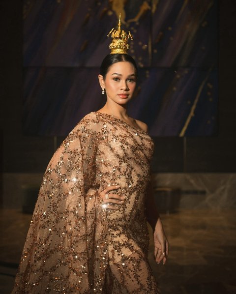 Tampilan Andien semakin memukau dengan kombinasi gaun sequin berwarna bronze dan hiasan kepala Thailand yang glamor.<br><br>