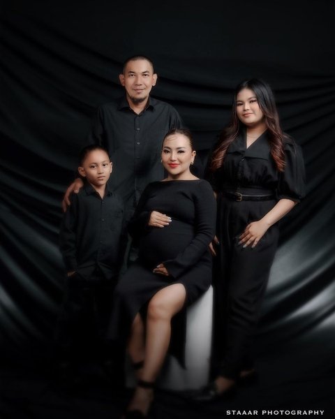 Salah satu maternity shoot yang dilakukan Mpok Alpa adalah foto keluarga dengan perut hamil, yang terlihat glamor dengan nuansa hitam.<br>