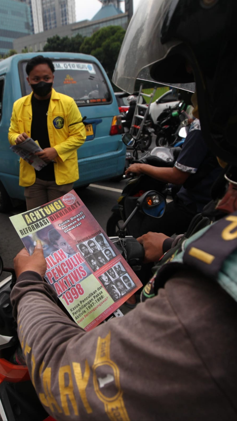 Pengendara sepeda motor membaca isi selebaran yang dibagikan mahasiswa UI.