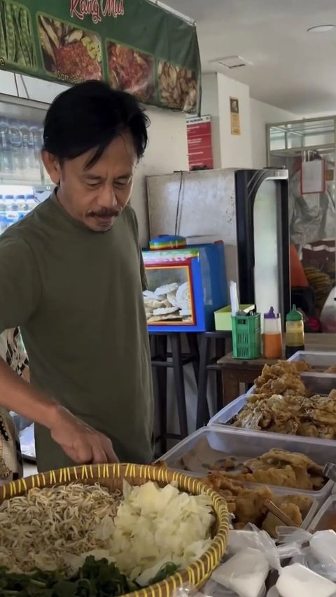 Epy memperlihatkan beragam makanan yang tersedia di warung. Mulai dari pastel, klepon, piscok, cilok, donat, hingga bubur sumsum