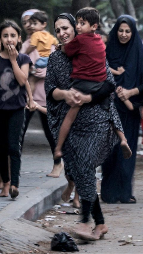 Kepanikan wanita Palestina bersama anak-anak mereka yang melarikan diri dari rumah mereka setelah serangan udara Israel di Kota Gaza, Jalur Gaza, pada 11 Oktober 2023. Mohammed Abed/AFP