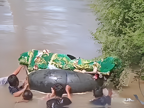 The Heartbreaking Portrait of Lampung Residents Swimming in a Swift River to Transport a Corpse with a Used Tire Due to Lack of a Bridge