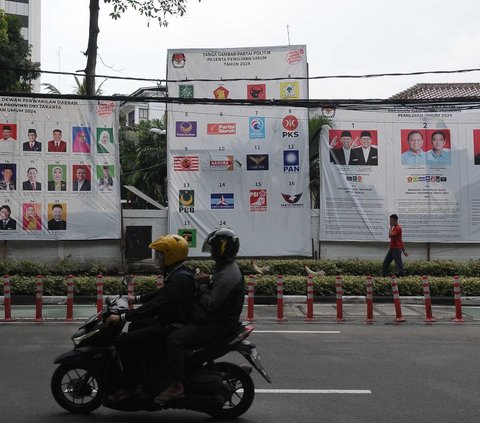 Pengendara melintas di depan baliho sosialisasi Pemilu 2024 di Jakarta, Sabtu (27/1/202). Pemilu 2024, yang digelar pada 14 Februari 2024, terhitung menyisakan 18 hari lagi. Foto: Merdeka.com/Imam Buhori<br>