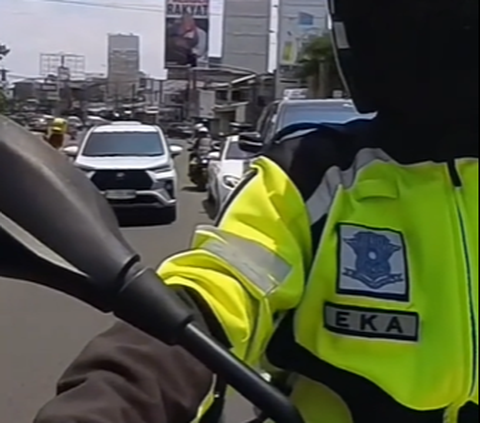 Seorang polisi pengawal menegur pengemudi sedan mewah bandel yang nekat mengikuti konvoi pejabat saat membelah kemacetan.