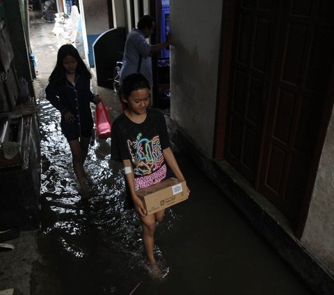 Warga beraktivitas di tengah banjir yang merendam lingkungan RT 16/04, Kelurahan Rawa Terate, Kecamatan Cakung, Jakarta Timur, Rabu (31/1/2024). Hujan yang mengguyur sejak malam  hari membuat pemukiman warga di Kelurahan Rawa Terate terendam banjir. Foto: Merdeka.com/Imam Buhori<br>