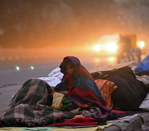 Seorang wanita tunawisma membungkus tubuhnya dengan selimut tebal saat beristirahat di pinggir jalan di New Delhi, India, Selasa (2/1/2024). Serangan musim dingin yang membuat suhu lebih rendah dari biasanya mengawali tahun 2024 di India.