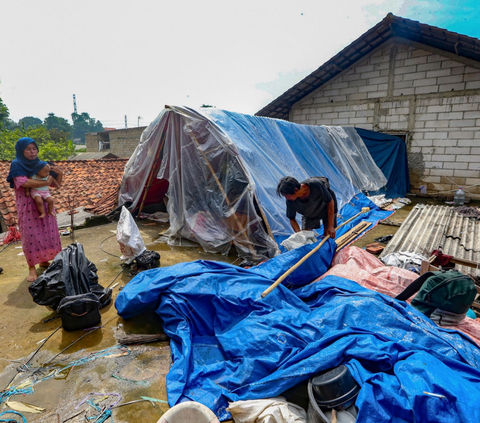 Warga beraktivitas saat akan mendirikan tenda darurat yang dibangun di atas rumah pasca banjir melanda kawasan Pejaten Timur, Jakarta Selatan, Senin (08/01/2024).