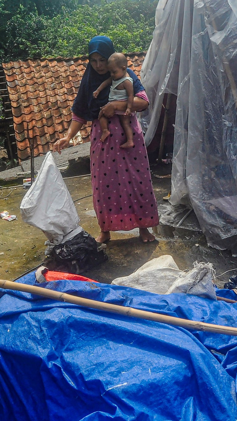 Aktivitas warga saat mengungsi di tenda darurat yang mereka bangun di atas rumahnya.