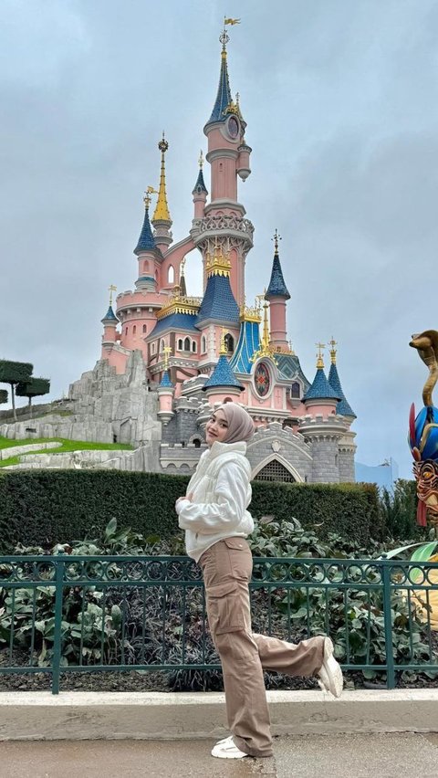 Putri Delina mengabadikan momen berlatar kastil yang menjadi ikon Disneyland.