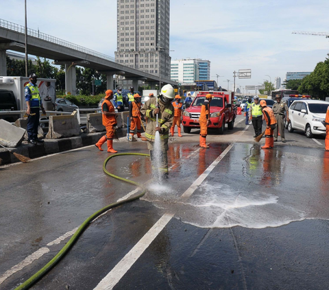Petugas berseragam oranye melakukan pembersihan sisa-sisa material kecelakaan mobil dump truk  di Jalan Gatot Subroto, Jakarta, Selasa (9/1/2024).