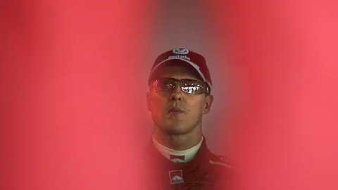 Pembalap Ferrari, Michael Schumacher tersenyum di paddock setelah sesi kualifikasi Formula 1 GP Bahrain di Sirkuit Sakhir pada 11 Maret 2006. (AFP/Loic Venance)