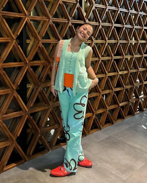 Alika Islamadina tampil dengan kebaya bermotif dipadukan celana putih putih panjang yang serasi dengan shoulder bag dan sneakersnya. [@alikaislamadina]