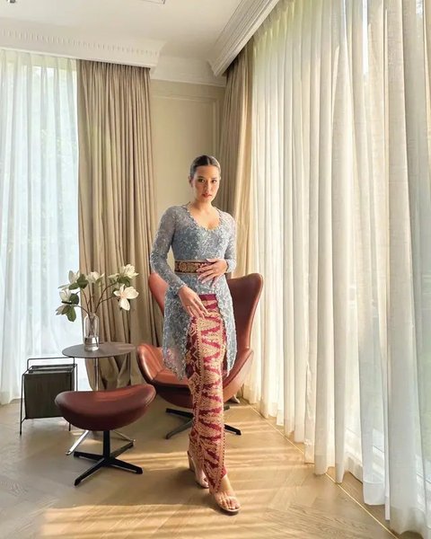 Kebaya Bali warna biru ini dipadukan dengan kain tenun Bali warna merah, lengkap dengan obi. [@raisa6690]