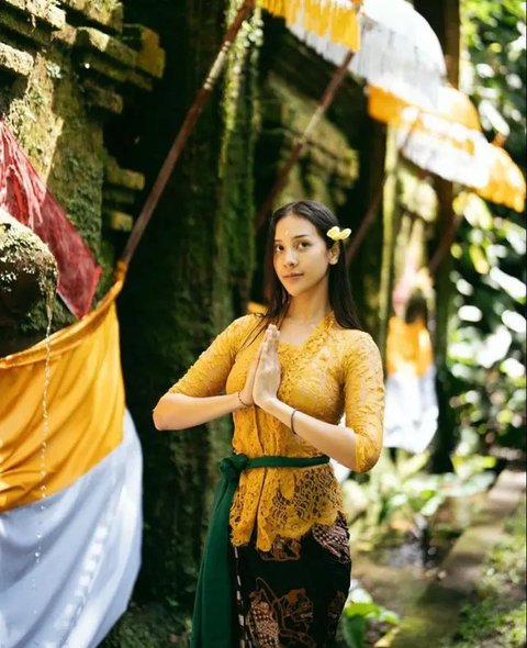 Kebaya Bali warna biru ini dipadukan dengan kain tenun Bali warna merah, lengkap dengan obi. [@raisa6690]