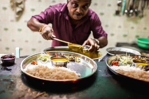 Seorang pedagang kaki lima menyiapkan makanan saat seorang pria makan di sebuah pasar grosir sayuran di Guwahati, India, Rabu (1/2/2023). Pemerintah Perdana Menteri India Narendra Modi mening