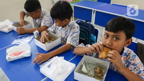 Terlihat siswa Sekolah Dasar (SD) Angkasa 5 Halim Perdanakusuma antusias menyantap makanan yang tersaji di dalam kotak. (Liputan6.com/Herman Zakharia)