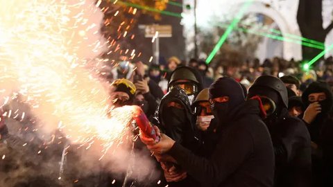 Pengunjuk rasa berkumpul di luar gedung parlemen pada Sabtu (30/11/2024) malam. Dalam aksinya, pengunjuk rasa melemparkan batu dan menyalakan kembang api. (Giorgi ARJEVANIDZE/AFP)