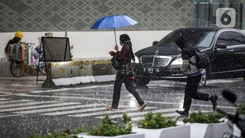 Warga menerjang hujan deras di kawasan Jalan Sudirman, Jakarta, Jumat (9/12/2022). Penjabat Gubernur DKI Jakarta Heru Budi Hartono menyebut pihaknya akan mengkaji penerapan bekerja dari rumah