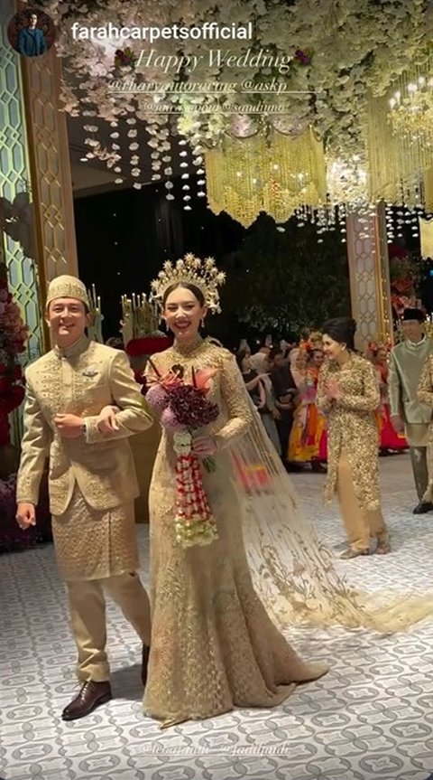 Mempelai pengantin memasuki venue dengan bergandengan tangan. Keduanya penuh senyum. Rio pun menyapa balik tamu yang menyapanya.