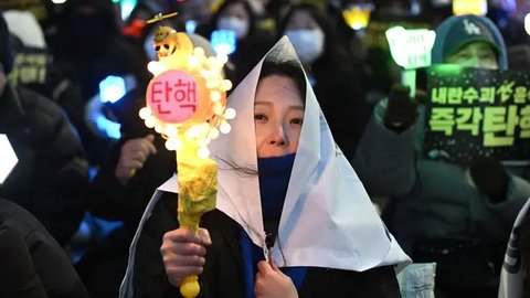 Salah satu pengunjuk rasa melambaikan tongkat cahaya (light stick) saat mereka mengambil bagian dalam protes yang menyerukan penggulingan Presiden Korea Selatan Yoon Suk Yeol di sebuah jalan dekat Majelis Nasional di Seoul pada tanggal 13 Desember 2024. (Jung Yeon-je/AFP)