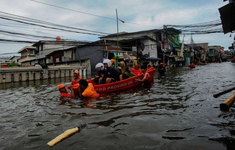 Petugas mengevakuasi warga menggunakan perahu  BPBD DKI saat banjir rob melanda kawasan Muara Angke, Jakarta, Senin (16/12/2024).