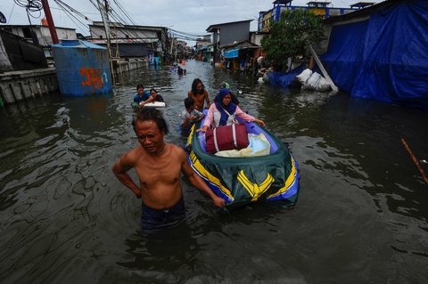 Sejumlah warga menggunakan perahu karet saat melewati banjir rob yang melanda kawasan Muara Angke, Jakarta, Senin (16/12/2024).