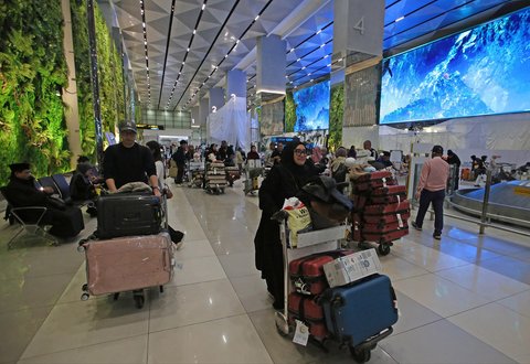 Penumpang pesawat  berjalan melewati lorong yang rimbun dengan suasana tanaman tropis dihiasi layar LED  di Terminal 3 Bandara Internasional Soekarno Hatta, Tangerang, Banten, Selasa (17/12/2024).
