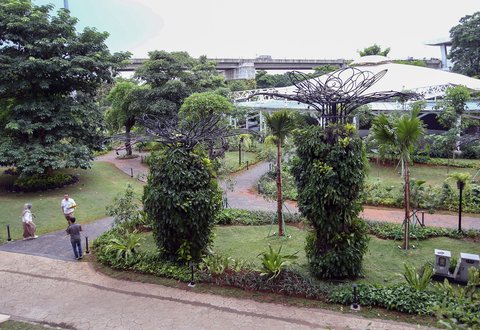 Penumpang pesawat  berjalan pada taman yang rimbun dengan suasana tanaman tropis di Terminal 3 Bandara Internasional Soekarno Hatta, Tangerang, Banten, Selasa (17/12/2024).