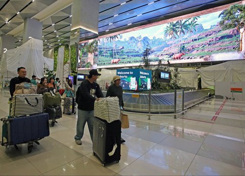 Penumpang pesawat  berjalan pada ruang bagasi yang dihiasi layar LED keindahan alam Indonesia  di Terminal 3 Bandara Internasional Soekarno Hatta, Tangerang, Banten, Selasa (17/12/2024).