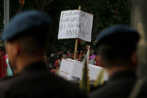 Mahasiswa mengangkat poster bertuliskan 'Berantas korupsi di negeri ini' saat berunjuk rasa menuntut penangkapan Harun Masiku di depan Gedung Merah Putih KPK, Jakarta, Rabu (18/12/2024).