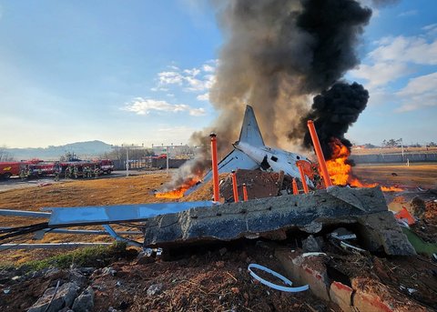 Asap mengepul hitam dari  bagian ekor pesawat Boeing 737-800 Jeju Air yang jatuh  jatuh dan terbakar di Bandara Internasional Muan di Provinsi Jeolla Selatan, Korea Selatan, Minggu (29 22/2024).