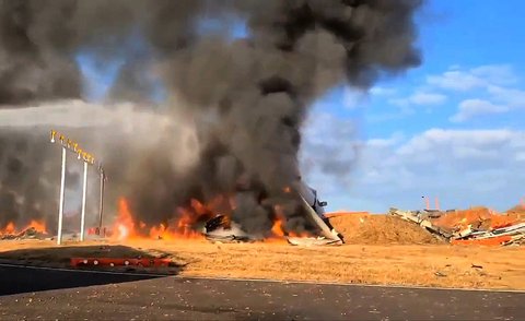 Asap mengepul hitam dari  bagian ekor pesawat Boeing 737-800 Jeju Air yang jatuh  jatuh dan terbakar di Bandara Internasional Muan di Provinsi Jeolla Selatan, Korea Selatan, Minggu (29 22/2024).