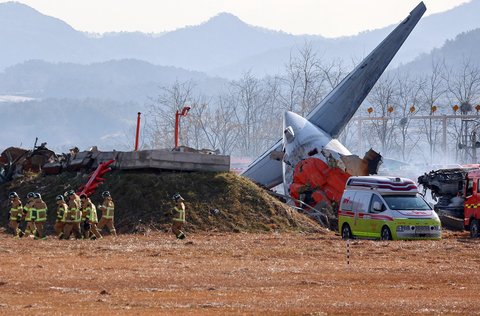 Tim SAR melakukan penyelamatan  di dekat bagian ekor pesawat Boeing 737-800  Jeju Air yang jatuh dan terbakar  di Bandara Internasional Muan di Provinsi Jeolla Selatan, Korea Selatan, Minggu (29/12/2024).