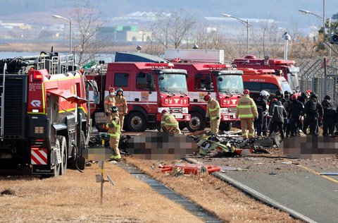Tim SAR melakukan penyelamatan  di dekat bagian ekor pesawat Boeing 737-800  Jeju Air yang jatuh dan terbakar  di Bandara Internasional Muan di Provinsi Jeolla Selatan, Korea Selatan, Minggu (29/12/2024).