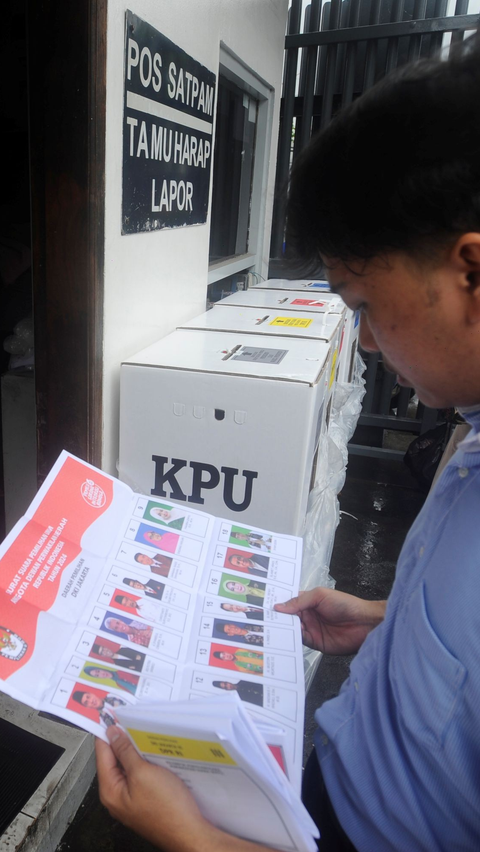 Seorang warga melihat gambar caleg pada salah satu surat suara saat melakukan pencoblosan pada TPS darurat. Foto: merdeka.com / Arie Basuki