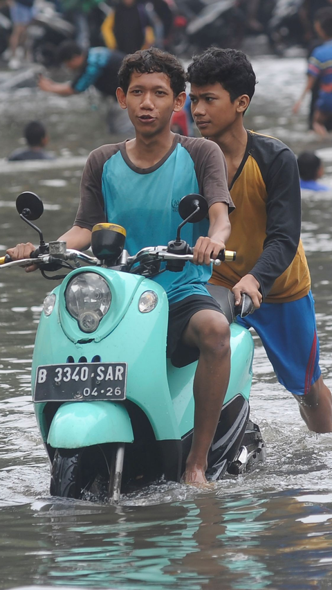 Akibat genangan yang cukup tinggi itu, sejumlah pengendara terpaksa mendorong kendaraannya. Foto: merdeka.com / Arie Basuki