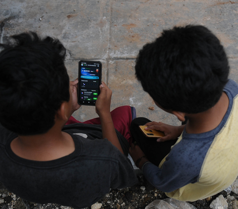Dua orang anak sedang melakukan pesanan makanan secara daring digital dengan aplikasi Gopay di Desa Kubang, Kabupaten Bogor, Jawa Barat, Sabtu (17/2/2024). Foto: merdeka.com / Imam Buhori