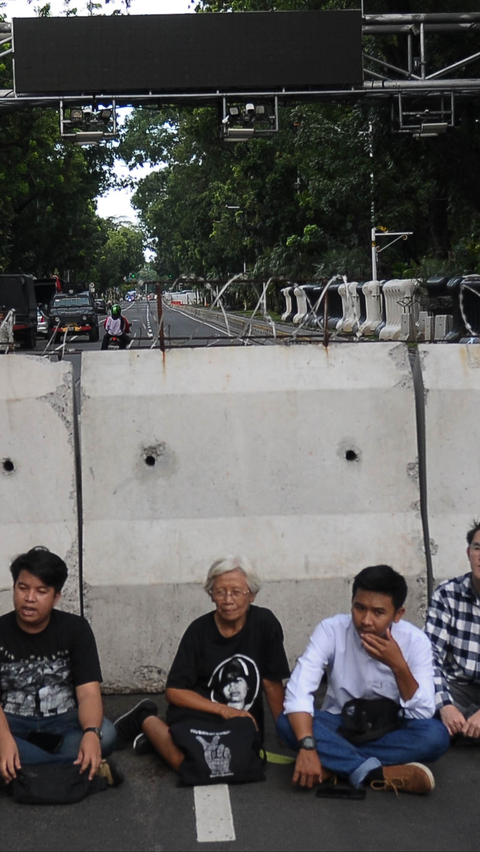 Ibu Maria terlihat berada di tengah-tengah mahasiswa dan duduk di depan pagar beton yang dipasang melintang di ruas jalan dari Patung Kuda menuju Istana Negara.<br>(Foto merdeka.com / Imam Buhori)<br>