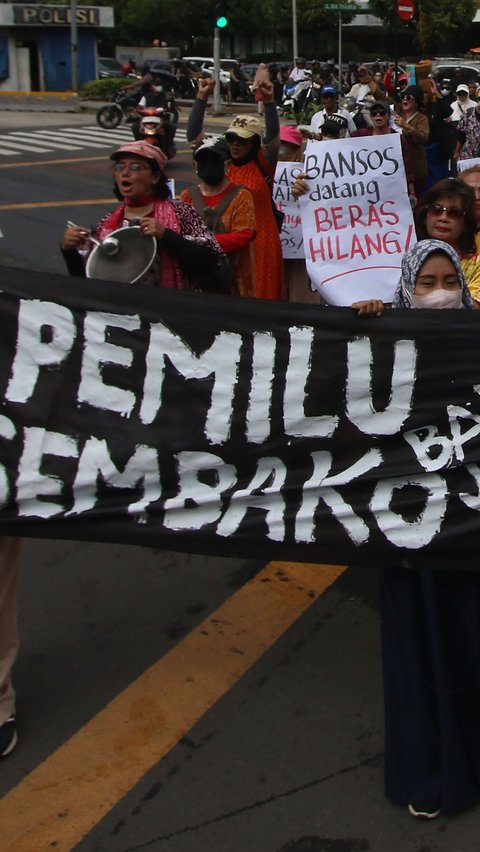 Emak-emak membentangkan spanduk hitam bertuliskan 'Pemilu banjir bansos, sembako jadi mahal'. Merdeka.com/Arie Basuki 