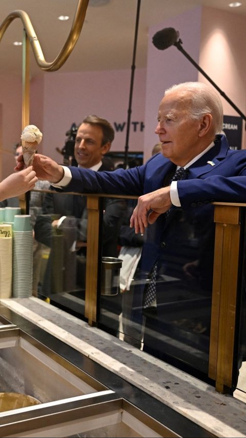 Presiden AS Joe Biden saat menerima es krim sebelum dinikmati bersama pembawa acara Seth Meyers di Van Leeuwen Ice Cream. Foto: AFP / JIM WATSON