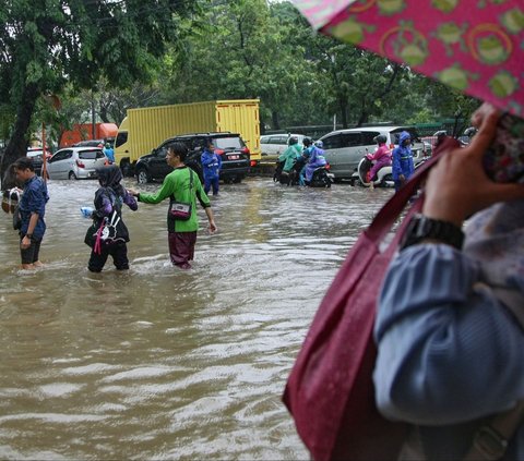 Sejumlah warga menerobos banjir yang menggenangi Jalan Suprapto, Cempaka Putih, Jakarta Pusat, Kamis (29/02/2024). Banjir parah ini terjadi setelah hujan lebat mengguyur Ibu Kota sejak Kamis dini hari. Merdeka.com/Arie Basuki