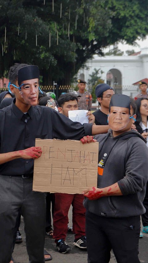 Aktivis Jaringan Solidaritas Korban untuk Keadilan memakai topeng Jokowi dan Prabowo saat mengikuti aksi Kamisan Ke-807 di seberang Istana Merdeka, Jakarta, Kamis (29/2/2024). Foto: Liputan6.com / Herman Zakharia