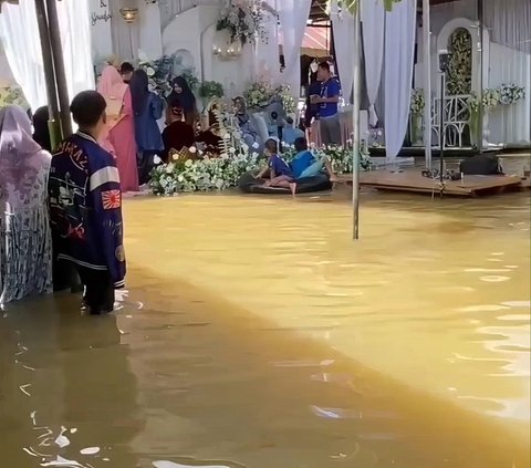 Residents Still Hold Wedding Celebrations Despite Floodwaters as High as Knees, Distracted by Children Playing in Water Near the Wedding Stage