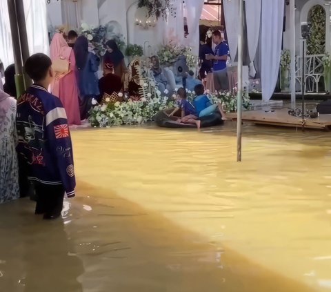 Residents Still Hold Wedding Celebrations Despite Floodwaters as High as Knees, Distracted by Children Playing in Water Near the Wedding Stage