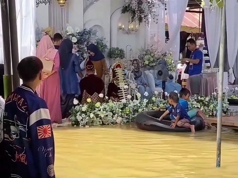 Residents Still Hold Wedding Celebrations Despite Floodwaters as High as Knees, Distracted by Children Playing in Water Near the Wedding Stage