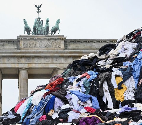 Gunungan sampah pakaian bekas dipajang oleh aktivis lingkungan Greenpeace di depan Gerbang Brandenburg, Berlin, Jerman, pada 5 Februari 2024. Aksi ini dilakukan untuk menentang tren fast fashion yang memiliki dampak buruk bagi lingkungan. REUTERS/Annegret Hilse